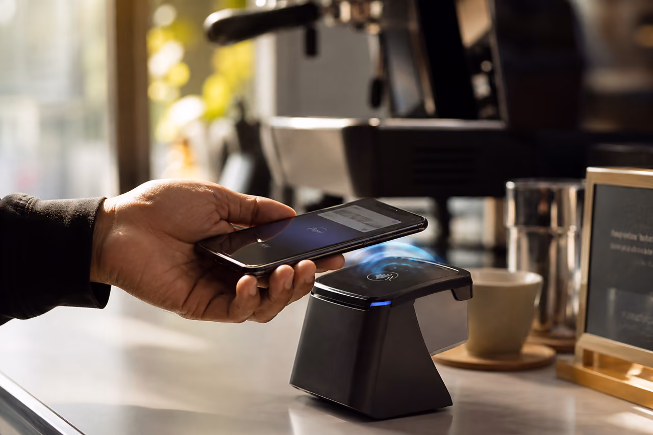 Person Using Smartphone for Contactless Payment at Cafe Terminal