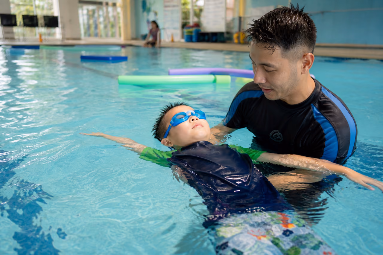 Swim Instructor Teaching a Child in an Indoor Pool