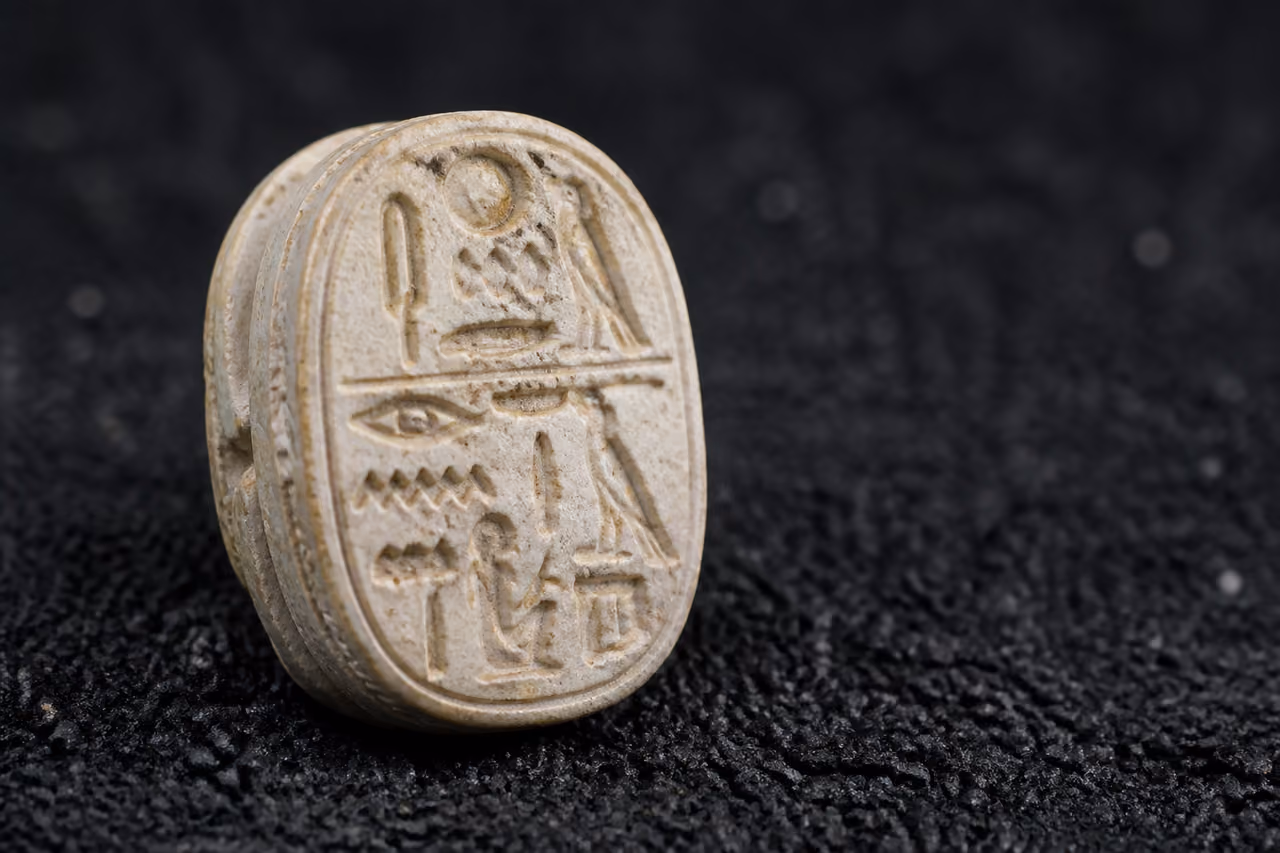 Ancient Egyptian Steatite Scarab Amulet on Dark Sand