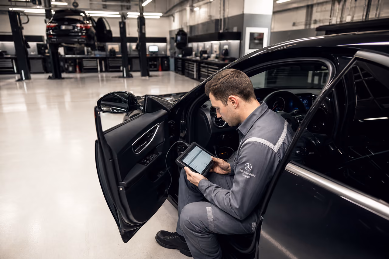 Technician Performing Diagnostics on Luxury Sedan in Professional Garage