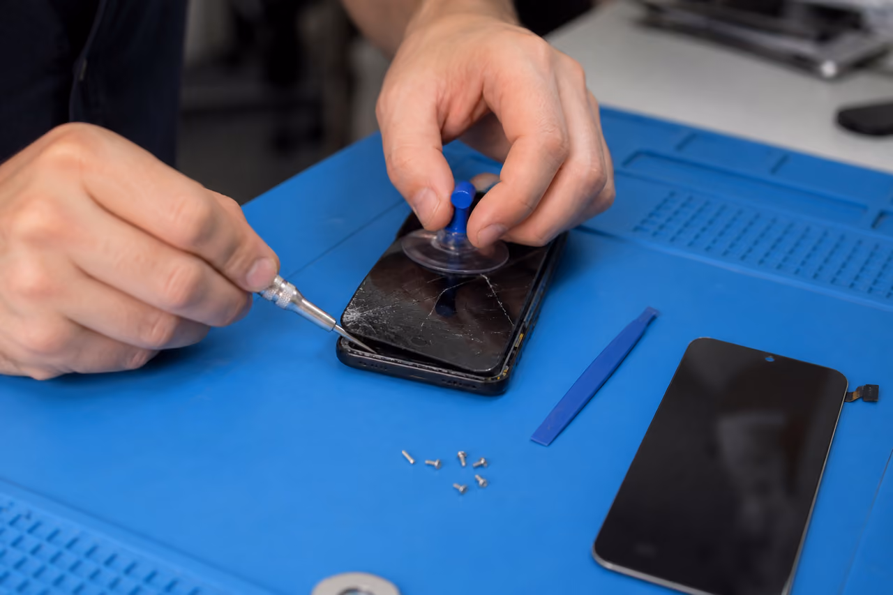 Technician Repairing a Cracked Smartphone Screen in a Workshop