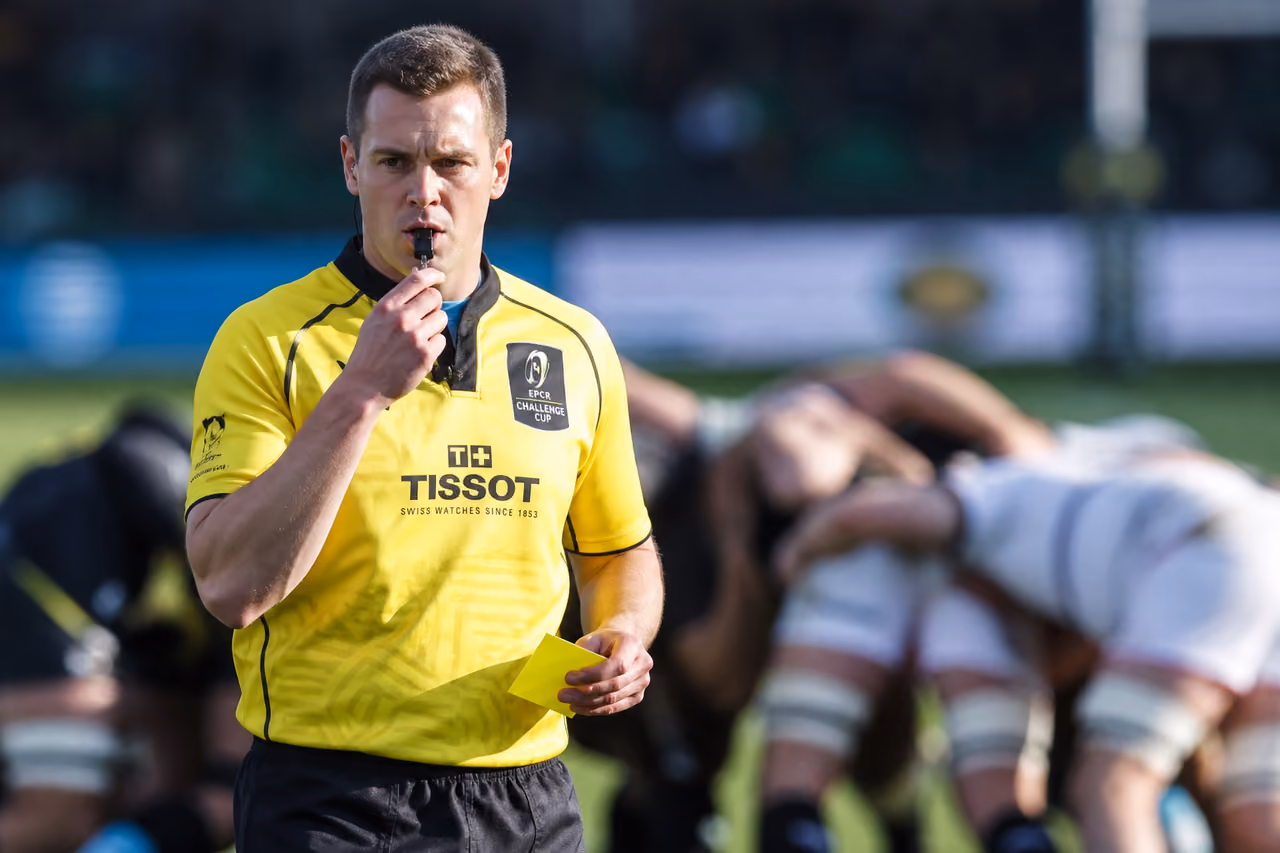 Rugby Referee Holding a Yellow Card on a Grass Pitch