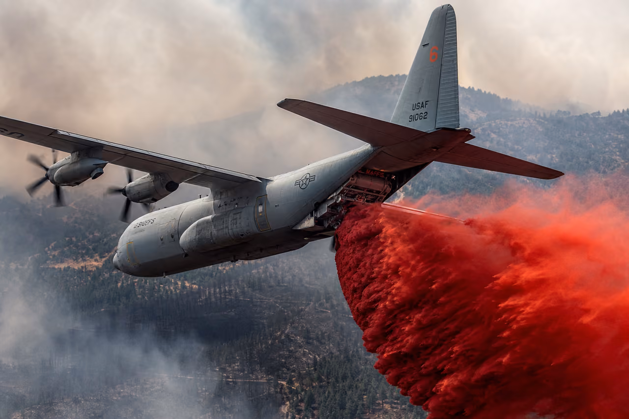 C-130 Aircraft Dropping Red Fire Retardant Over Forest Fire