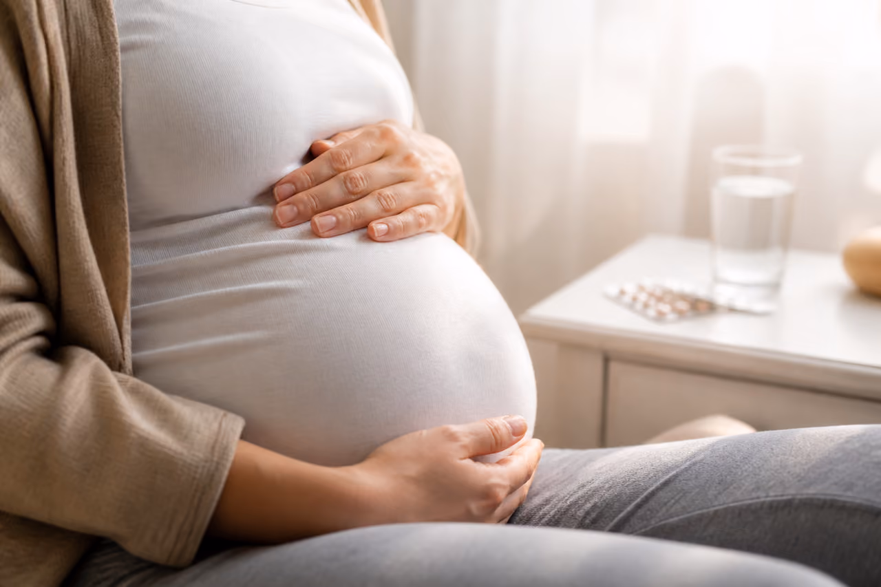 Pregnant Woman Cradling Belly Near Prenatal Supplements