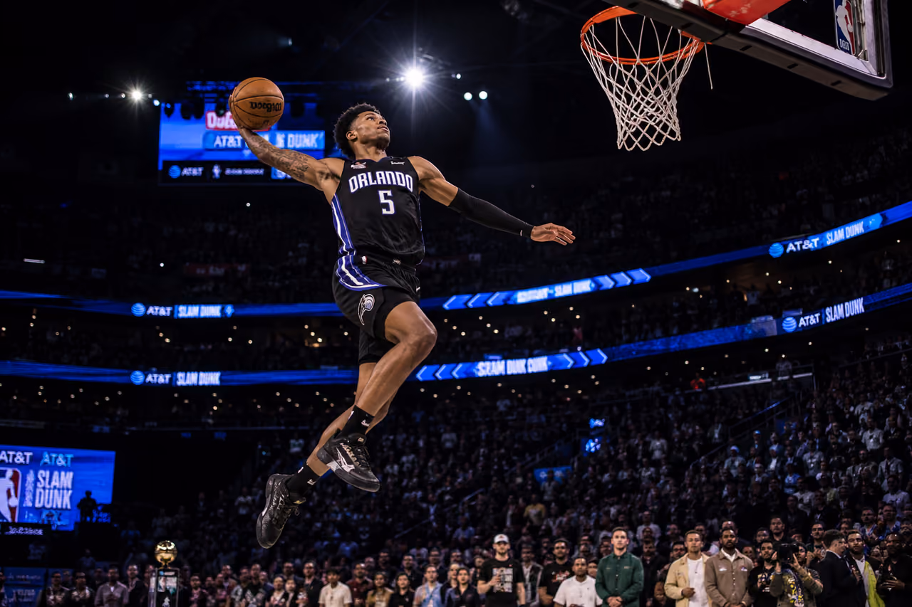 Professional Basketball Player Performing a Slam Dunk in an Arena