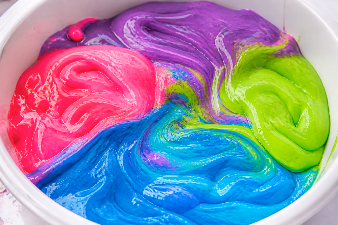 Hands Mixing Colorful Giant Slimes in a Clear Basin