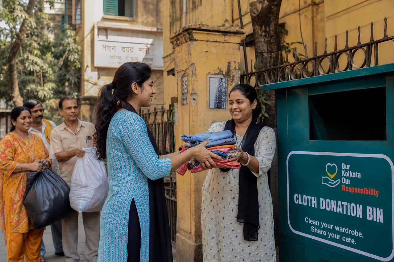 People Donating Folded Clothing to a Community Bin in Kolkata